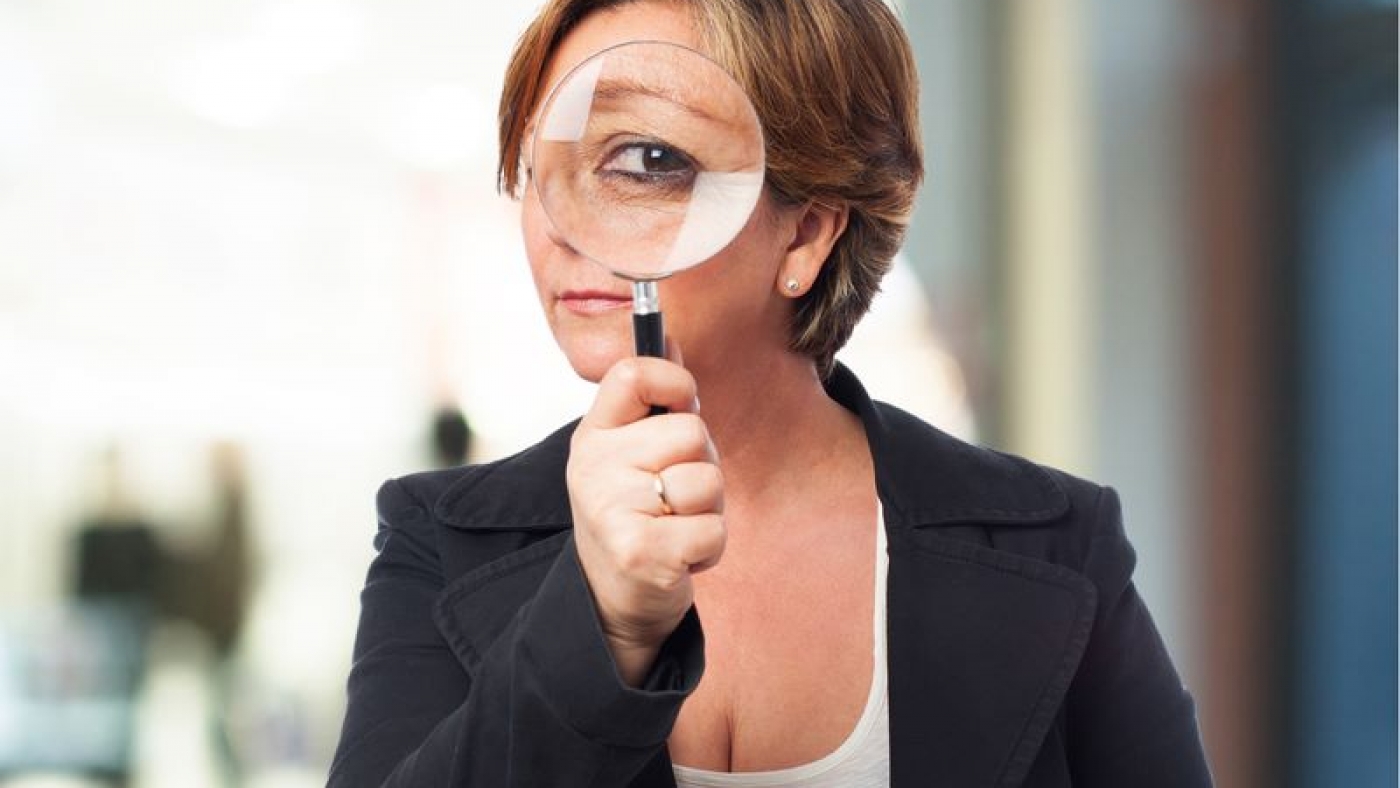portrait of a mature business woman looking through a magnifying glass