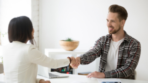 Smiling millennial partners handshaking in office thanking for successful teamwork, happy male manager and satisfied female client or customer shaking hands making deal, thanking for help or support