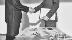 Two businessmen in formalwear handshaking after signing contract
